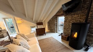 Una sala de estar acogedora con una pared de piedra, una chimenea, un sofá y una televisión.