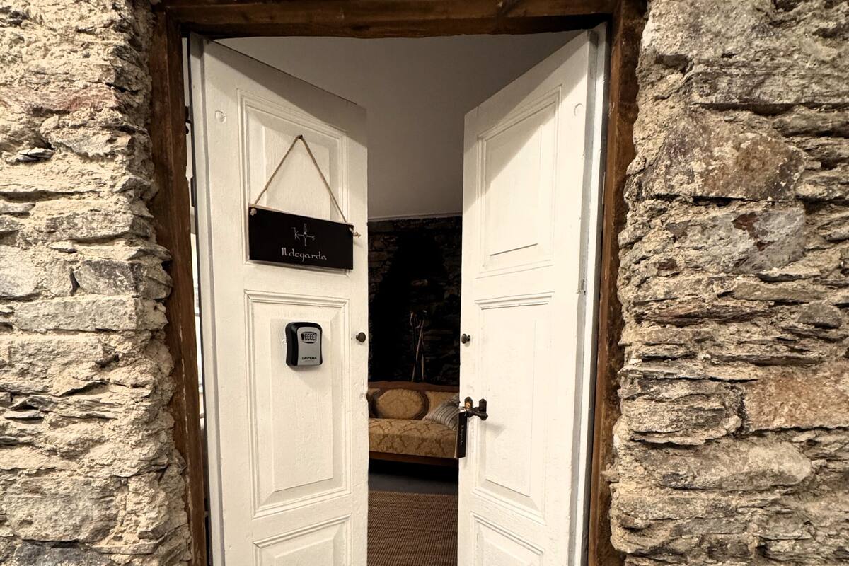 A stone-walled room with a bed and a sign reading "Albergarda".