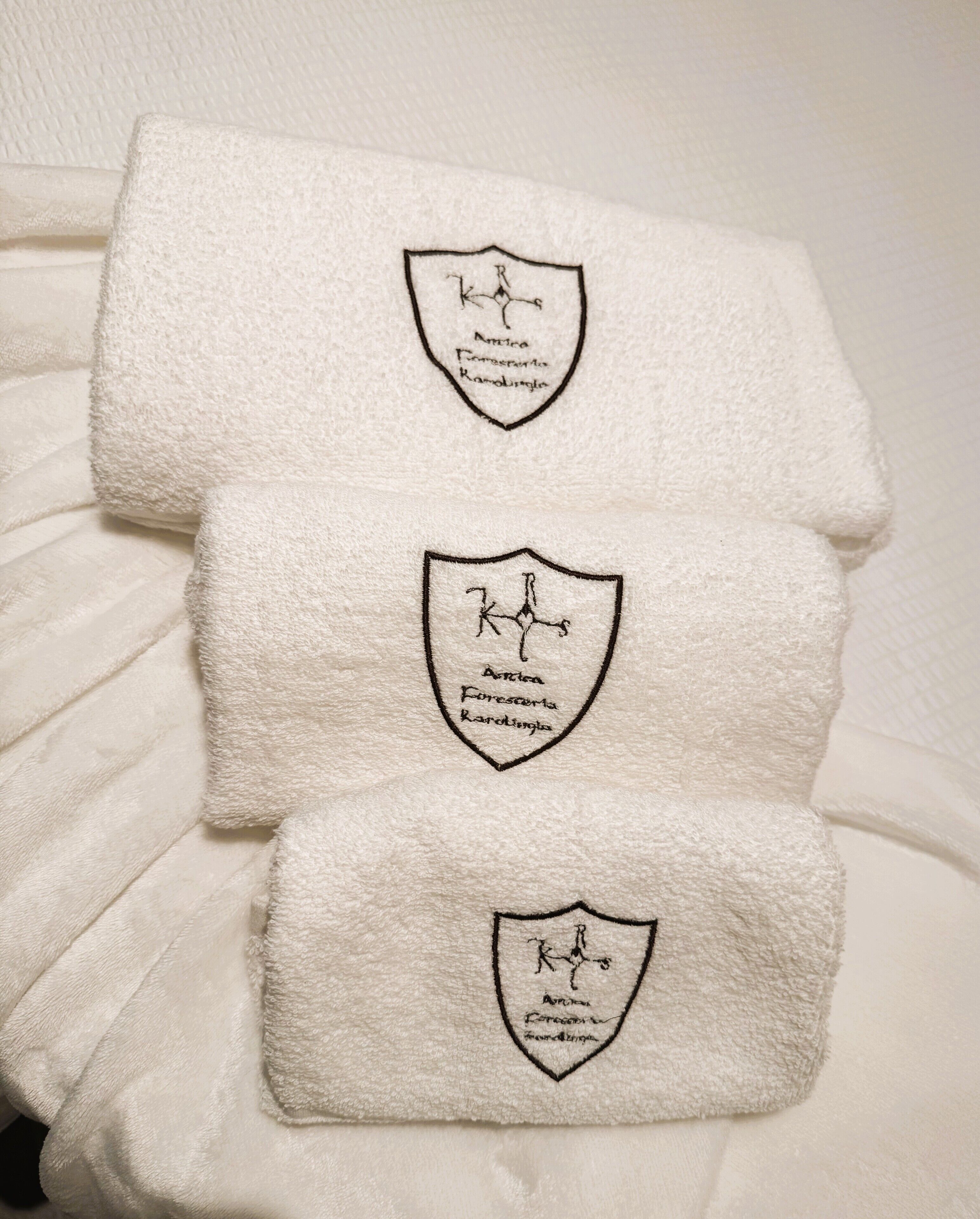 Three white towels with embroidered logos on a white surface.