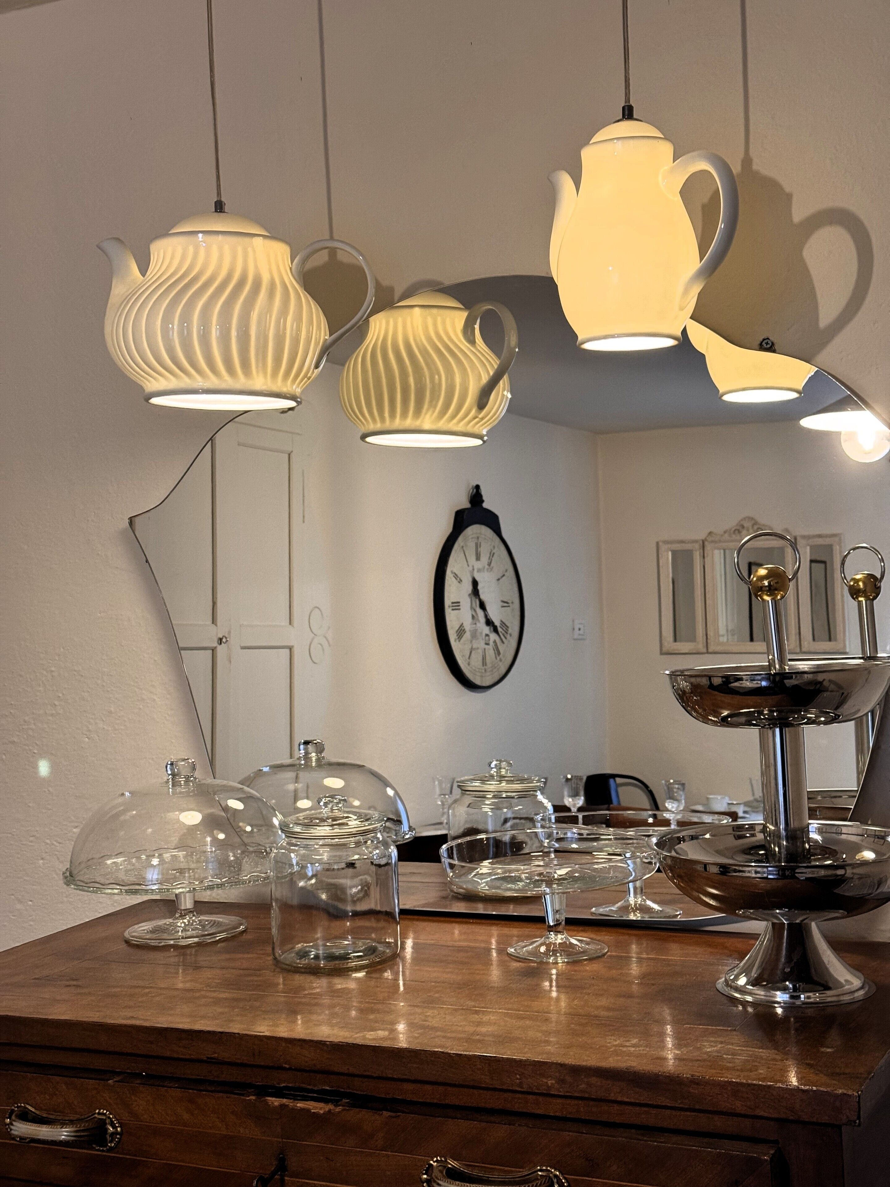 Un coin repas avec une table en bois, de la vaisselle transparente et une horloge au mur.