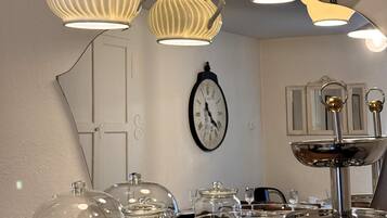 Un coin repas avec une table en bois, de la vaisselle transparente et une horloge au mur.