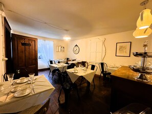 Een eetgedeelte met gedekte tafels, een klok aan de muur en een deur naar buiten.