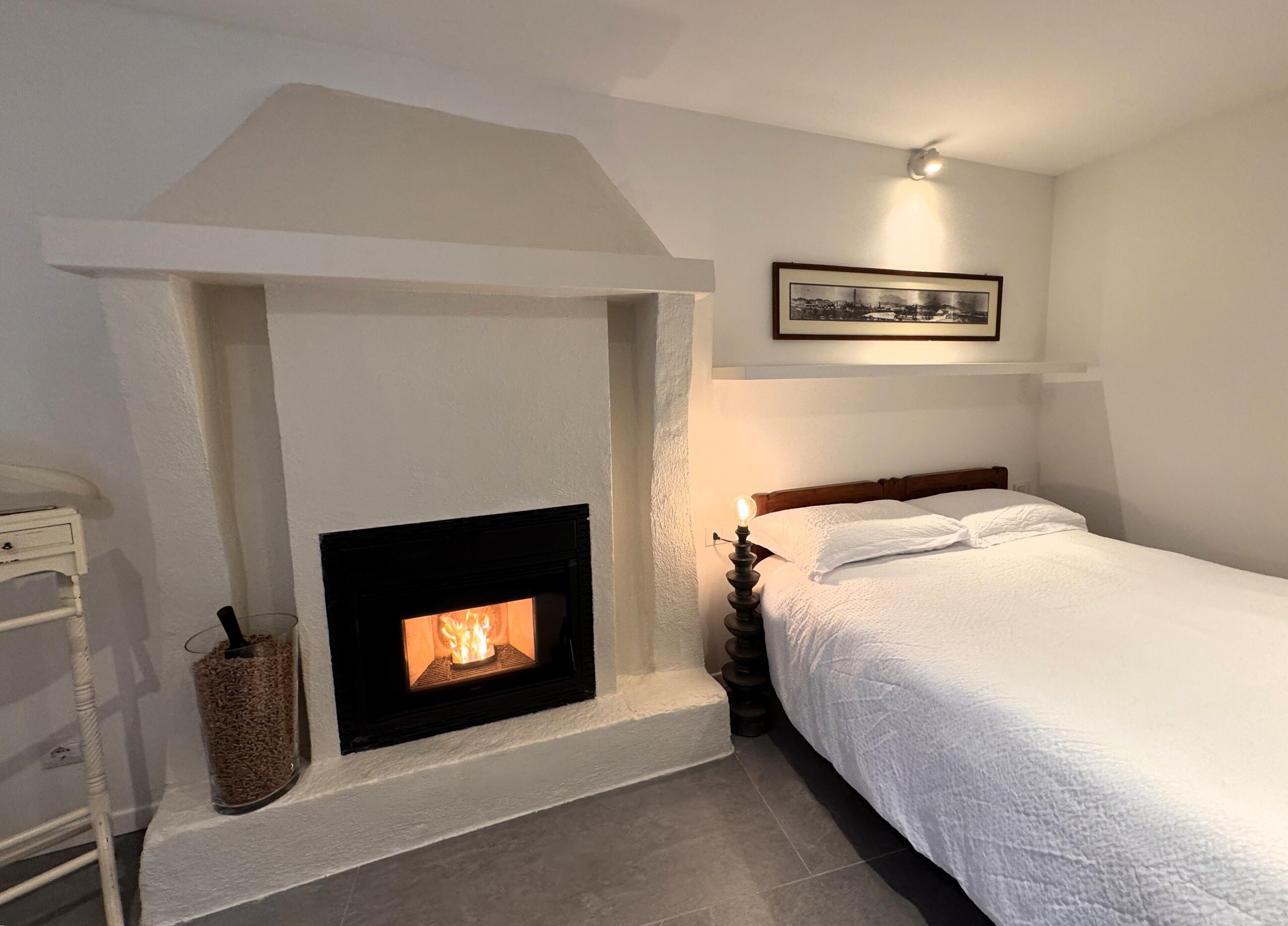 Un dormitorio con chimenea, una cama y un cuadro en la pared.