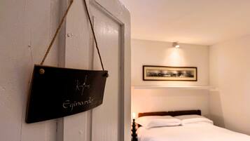 Een hotelkamer met een bed, een inlijsting foto aan de muur en een hangend bord met tekst.