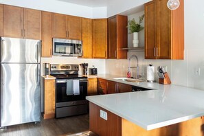 A modern kitchen with wooden cabinets, stainless steel appliances, and a large island.