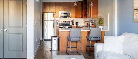 Una cocina moderna con armarios de madera, electrodomésticos de acero inoxidable y una isla central con taburetes de bar.