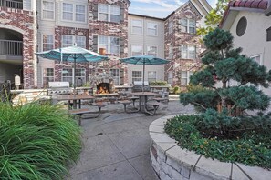 A patio area with outdoor seating, a stone fireplace, and a small tree.