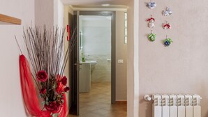 Ein Flur mit einer zur Toilette führenden Tür, einem Heizkörper und Wanddekorationen.