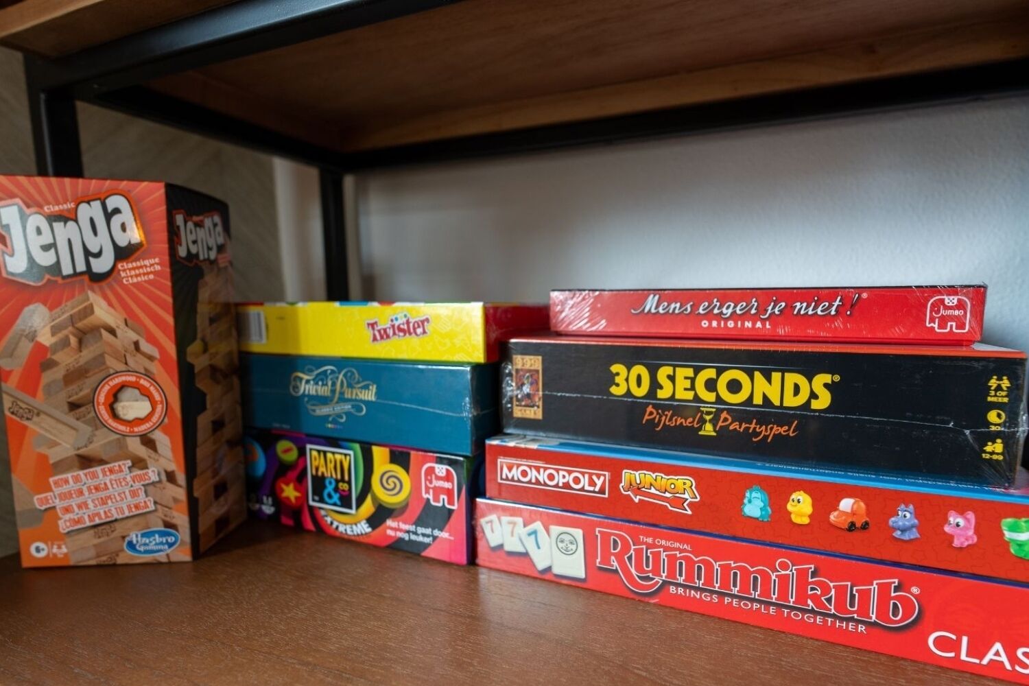 Une étagère contenant divers jeux de soci été, notamment Jenga, Twister, 30 Seconds, Monopoly et Rummikub.