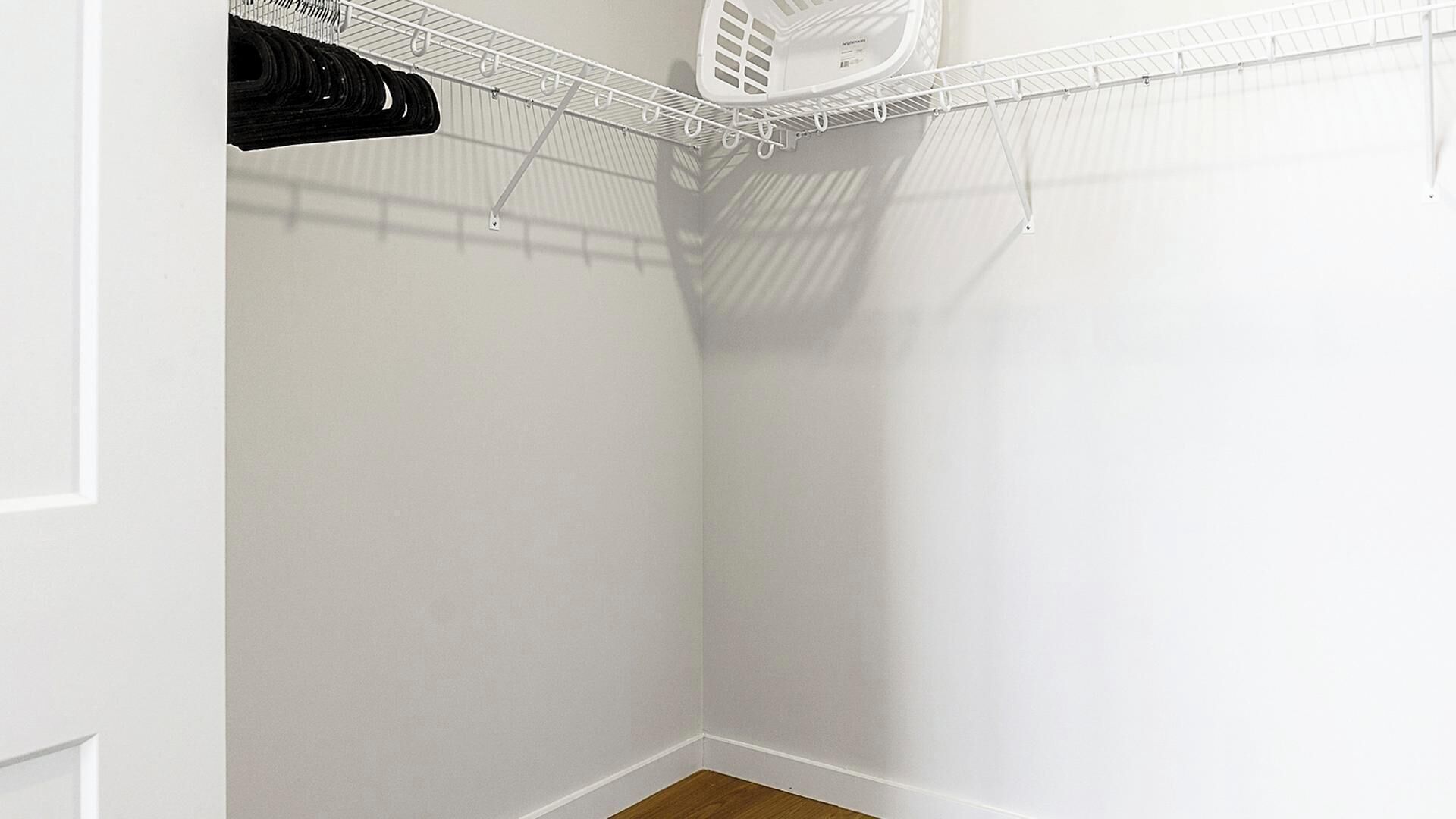 Ein weißer Kleiderschrank mit einem Metallgitterregal und einem weißen Kunststofftrockner.