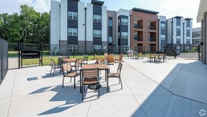 Moderni kerrostalo, jossa on ulkotiloja oleskelua varten ja aidattu sisäpiha.