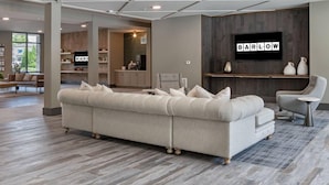 Ein modernes Wohnzimmer mit einer Eckcouch, einer Bar und einem an der Wand befestigten Fernseher.
