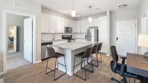 Een moderne keuken met witte kastjes, een roestvrijstalen koelkast en een centraal eiland met barstoelen.