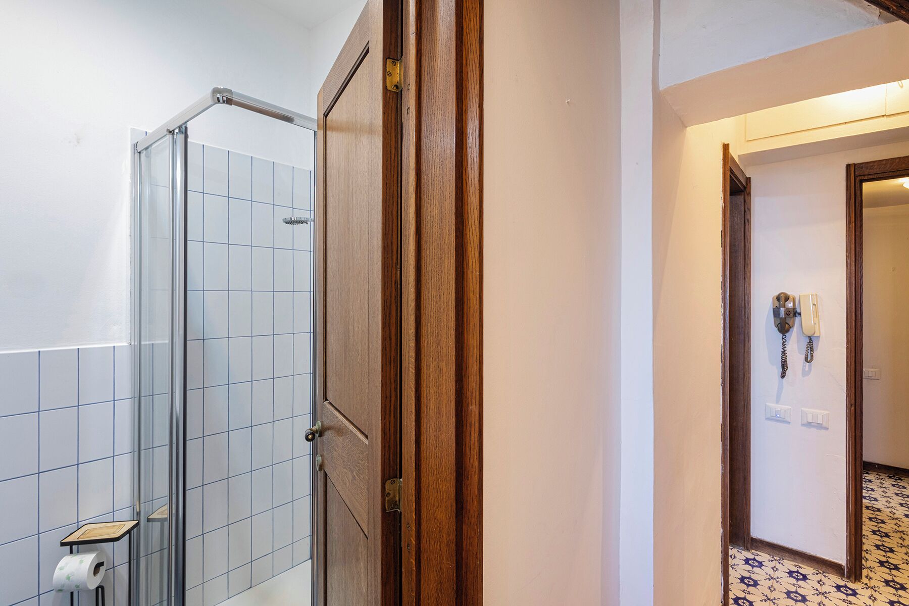 A bathroom with a shower, a toilet, and a wooden door.