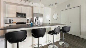Eine moderne Küche mit einer zentralen Kochinsel, Barhocker, Edelstahlgeräten und einem minimalistischen Design.