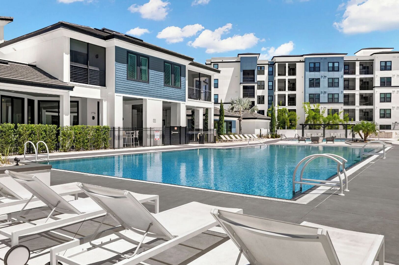 Un hôtel moderne doté d’une piscine, de chaises longues et d’un jardin aménagé.