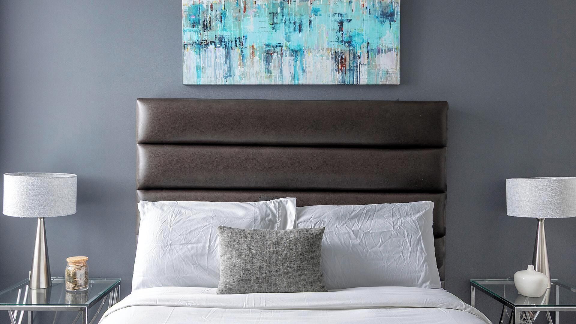 A modern bedroom with a dark brown upholstered headboard, white bedding, and two bedside tables with lamps.