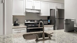 A modern kitchen with white cabinets, a stainless steel refrigerator, a built-in microwave, a stove, and a sink with a faucet. - Landing | Stunning 1BD, Clubhouse, Pool (Atlanta)