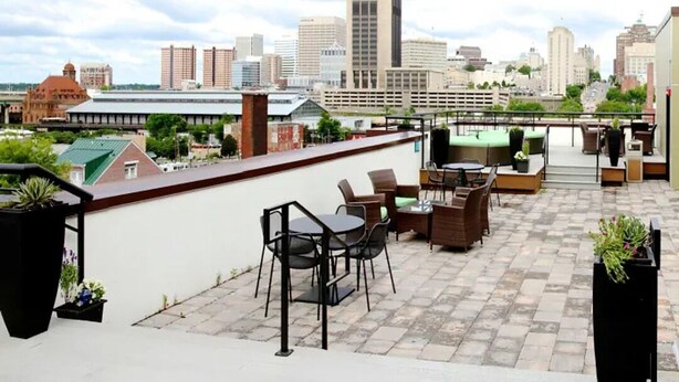 Una terraza en la azotea con mobiliario exterior, un horizonte urbano de fondo y vistas del paisaje citadino.