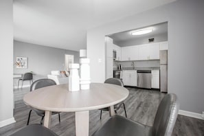 Una cocina moderna con armarios blancos, electrodomésticos de acero inoxidable y encimera gris.