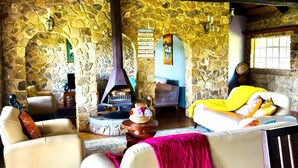 Un salón acogedor con paredes de piedra, chimenea y asientos cómodos.