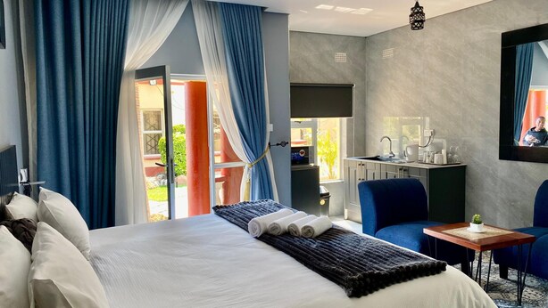 A hotel room with a bed, a desk, a chair, and a TV. - Executive studio apartment near the airport - 2320 (Harare)