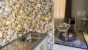 Une cuisine avec un mur de pierre derrière l’évier, un évier en acier inoxydable et une chaise au design moderne.