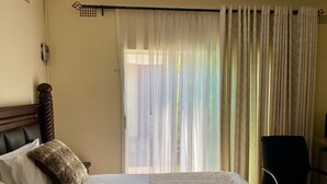 A hotel room with a bed, a chair, and a window with curtains.