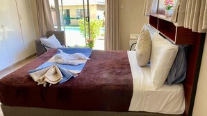 Habitación de hotel con cama, una silla, un escritorio y vistas al exterior.