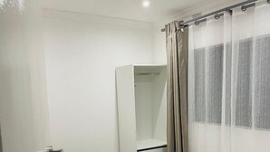 Une chambre à coucher avec un lit, une armoire et une fenêtre avec des rideaux.