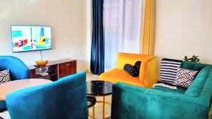 Een woonkamer met een bank, fauteuils, een salontafel, een televisie en een kast.