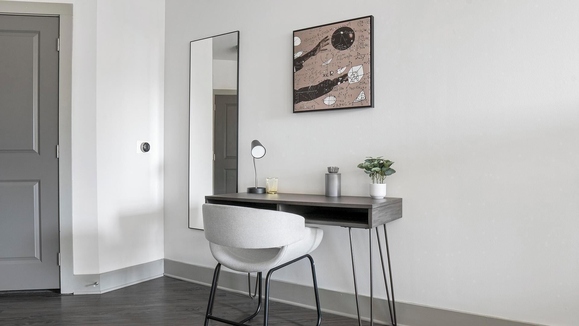 A modern office space with a desk, chair, and a large mirror.