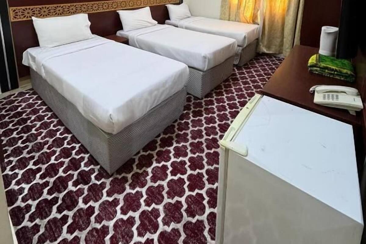 Une chambre d’hôtel avec deux lits, un bureau avec un téléphone et une moquette à motifs.
