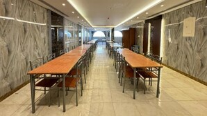 Een congreszaal met lange tafels en stoelen, marmeren wanden en een plafond met inbouwverlichting.