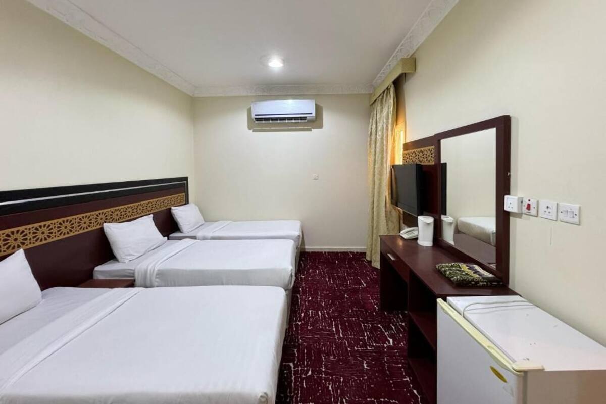 Une chambre d’hôtel avec deux lits, un bureau, un miroir, un appareil de climatisation et un téléviseur.