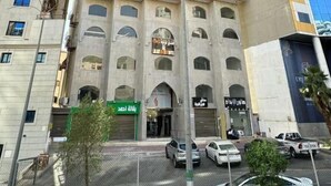 Een meerlaags gebouw met een centrale ingang, meerdere ramen en een groene luifel.