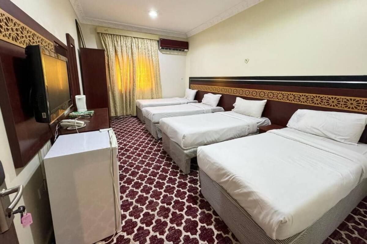 Une chambre d’hôtel avec quatre lits simples, une télévision, un bureau et un mini-bar.