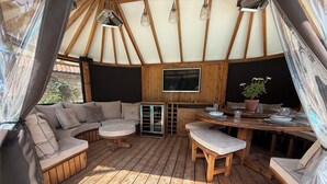 A wooden deck with a sofa, round table, and benches. - Granary Cottage (Chippenham)