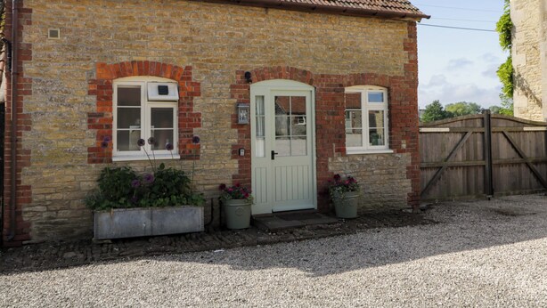 A brick house with a tiled roof, a white door, and two windows. - Granary Cottage (Chippenham)