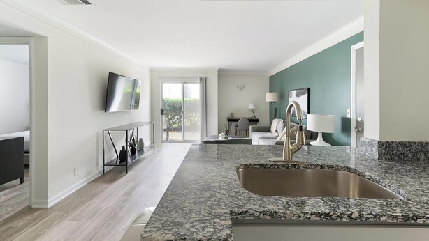 A modern kitchen with granite countertops, a stainless steel sink, and a dining area with a table and chairs. - Landing | Stunning 1BD, Courtyard, Pool (Nashville)