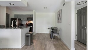 A compact kitchen with a central island, built-in appliances, and a small dining area. - Landing | Stunning 1BD, Courtyard, Pool (Nashville)