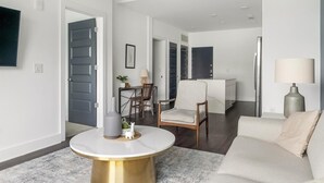 Een moderne woonkamer met een ronde salontafel, een bank en een eethoek met stoelen en een tafel.