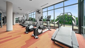 Een fitnessruimte met cardioapparatuur, krachttoestellen en een bank.