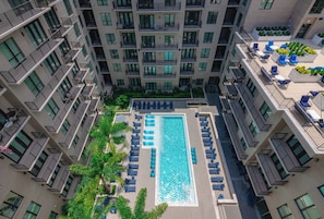 Ein Hochhaus mit Pool auf dem Dach, umgeben von Liegestühlen und Palmen.