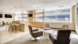 Un intérieur moderne avec un bar, des espaces pour s’asseoir et de grandes fenêtres offrant une vue panoramique.