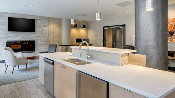 Une cuisine moderne dotée d’un îlot central, d’un lave-vaisselle intégré et de luminaires suspendus.