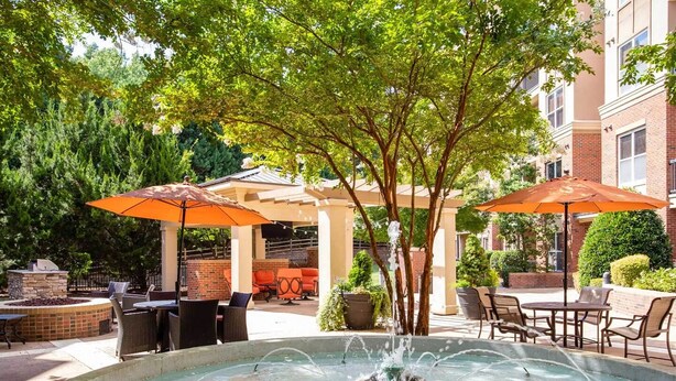 Un espace extérieur aménagé en patio, avec une fontaine, des sièges abrités et des parasols.