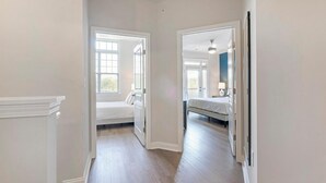 Un couloir mène à deux chambres dotées de murs blancs et de planchers en bois.