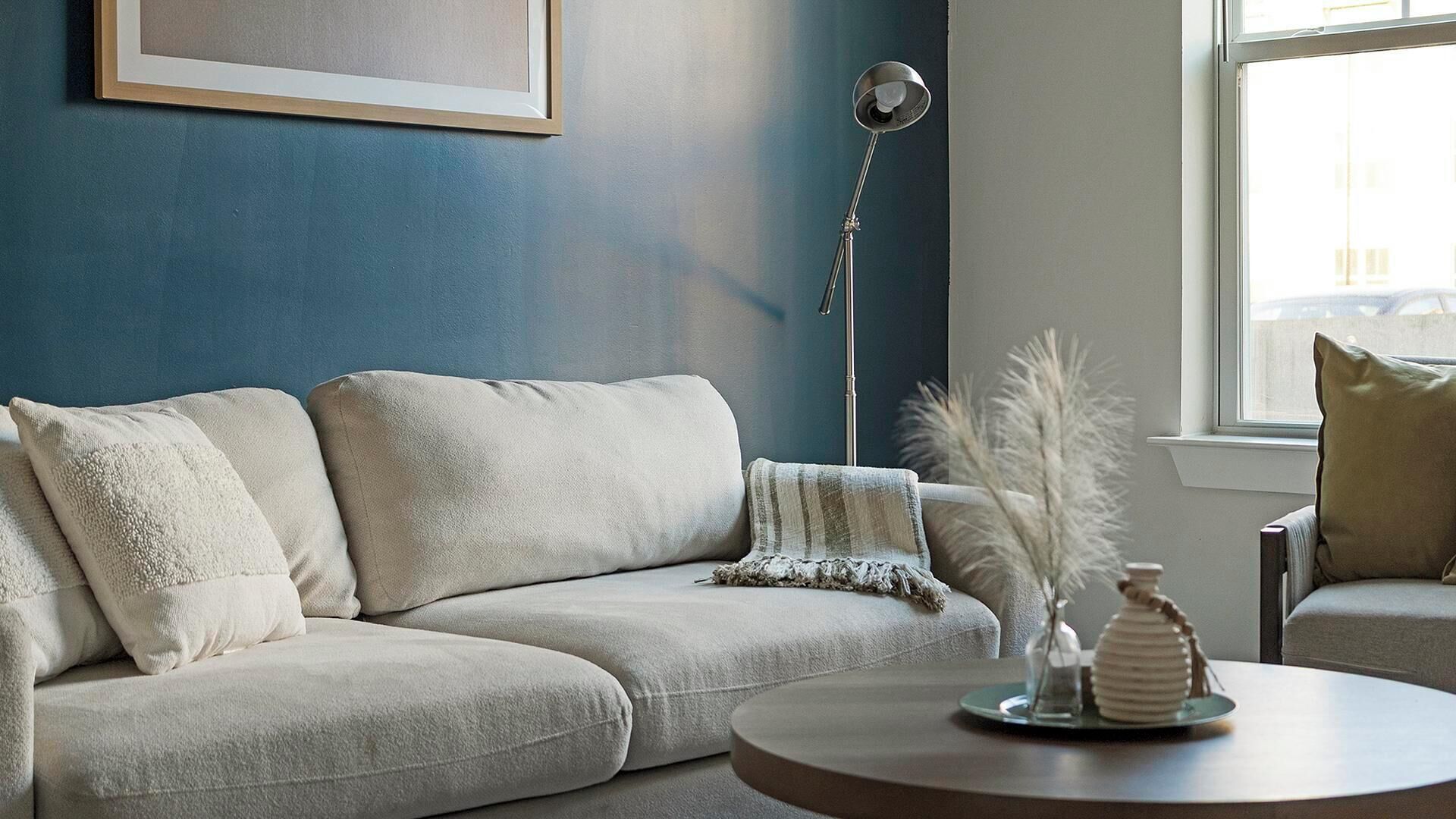 Ein Wohnzimmer mit einer Couch, einem runden Couchtisch und einer Stehlampe.