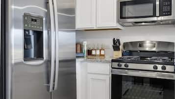 A modern kitchen with stainless steel appliances, including a refrigerator, microwave, and oven.